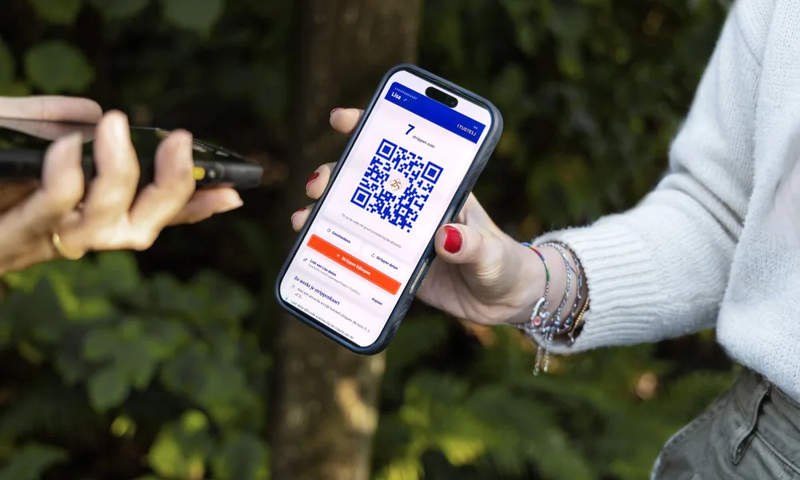 Een medewerker scant de QR-code op de strippenkaart van een bezoeker bij een attractie